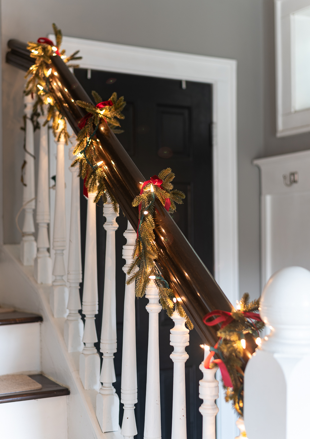 Red, White, Green Christmas Entry Decorating Ideas - Red Velvet Bow on Wreath - Lighted Garland with Red Velvet Bows on Staircase - Decorating Ideas for Entry for Holidays